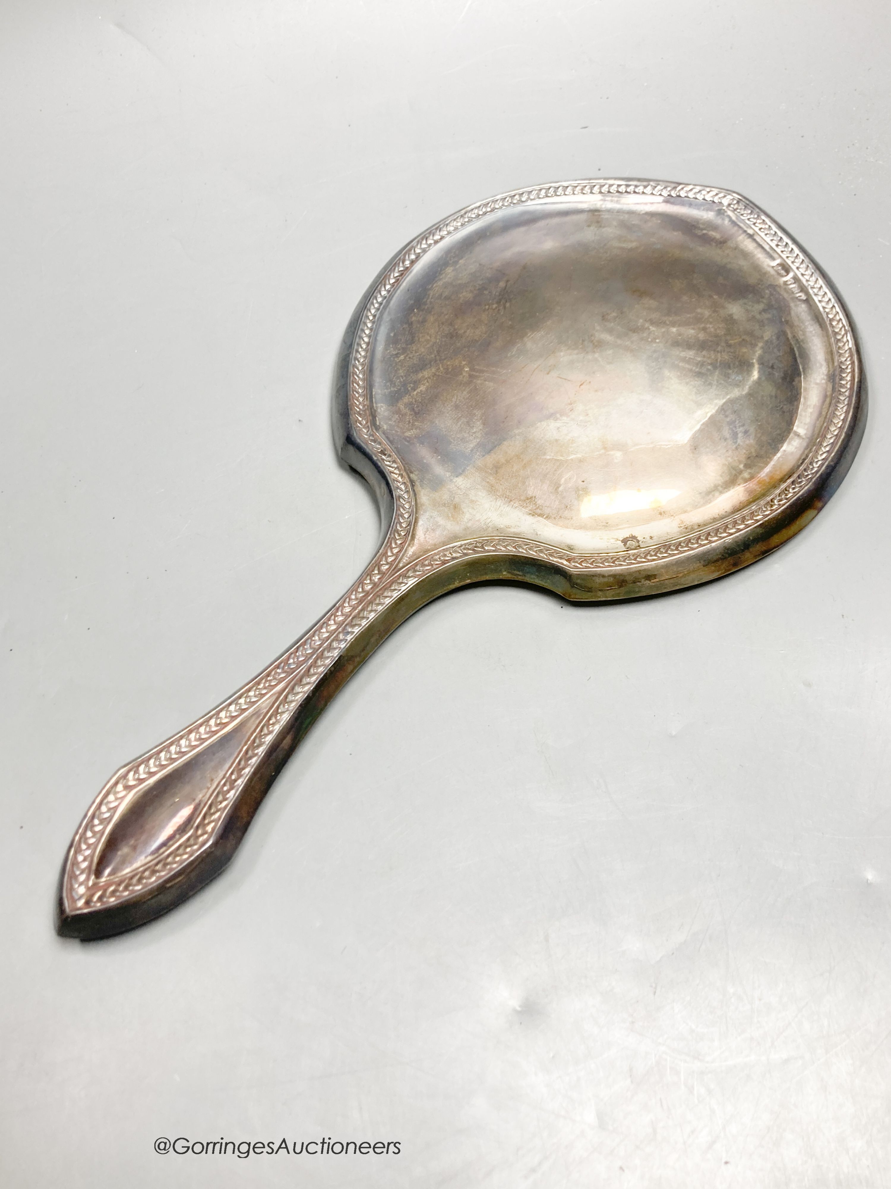 A George V silver mounted hand mirror and three silver cigarette cases.